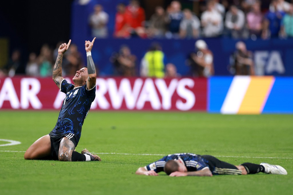 Enzo Fernandez celebrates on his knees while another player lies on the field after Argentina
